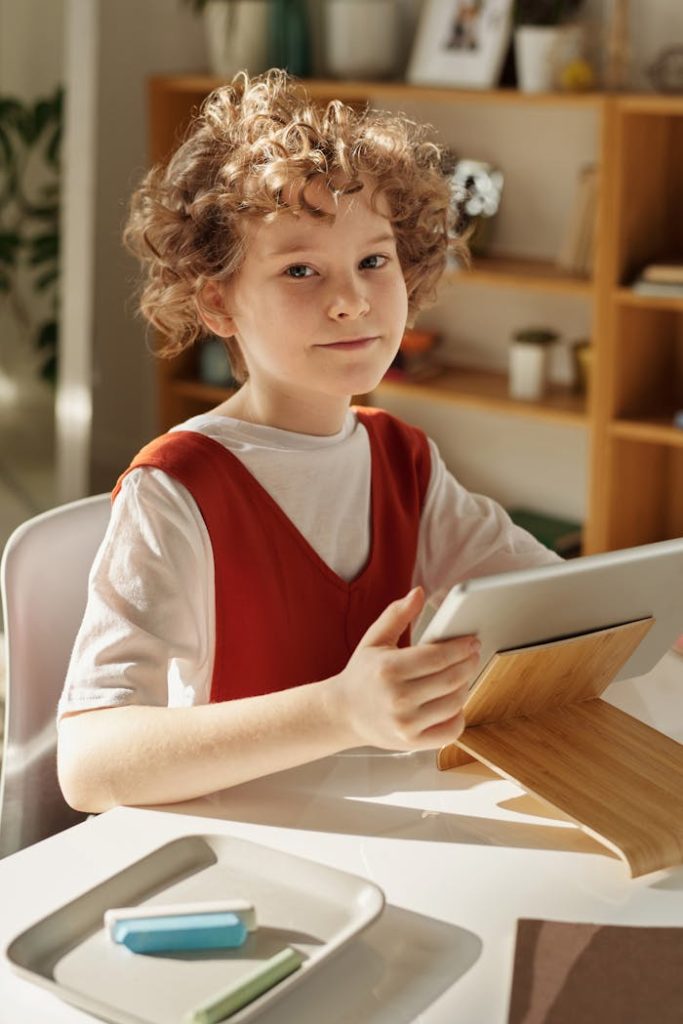 pexels-photo-4145075 Curly-haired girl using tablet for online learning at home, sitting at desk.